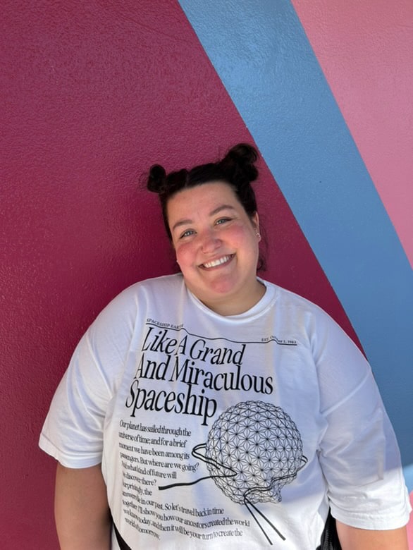 Girl wearing the building your future Spaceship Earth Disney-Inspired tee at Epcot in front of the bubble gum wall